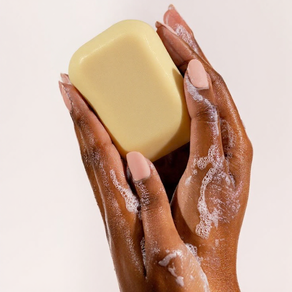 Alra unscented soap bar in hand mid-cleansing with visible suds